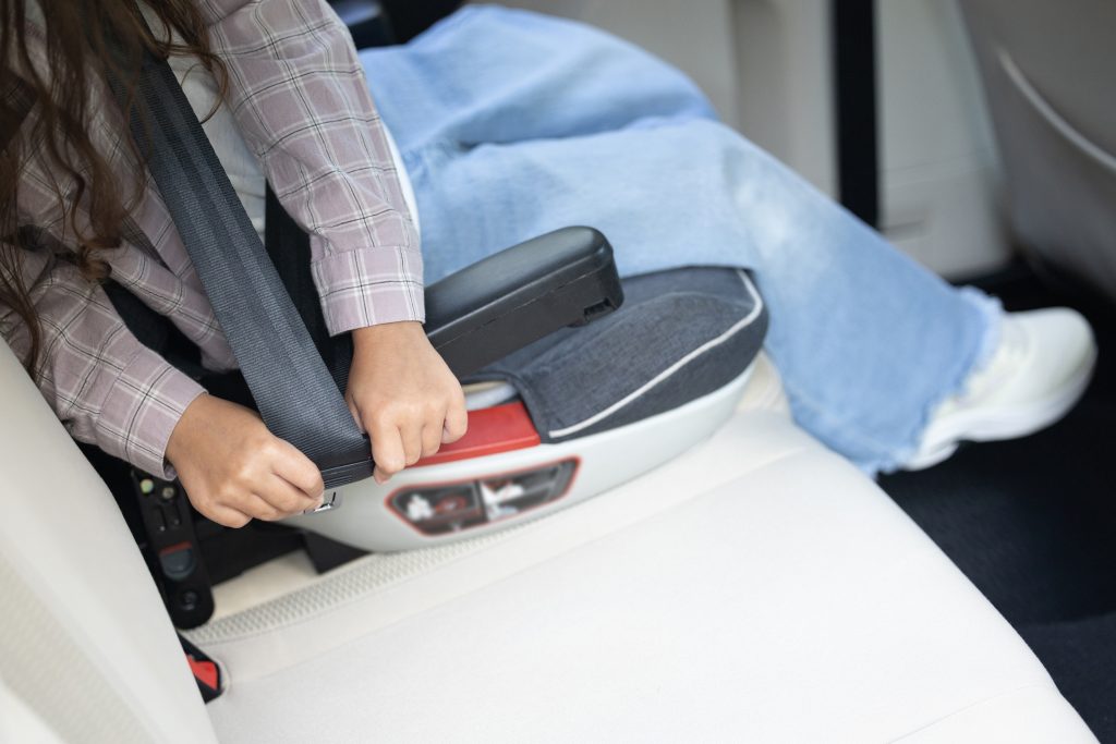 Close up picture of a kid sitting in a car with the seatbelt fixed