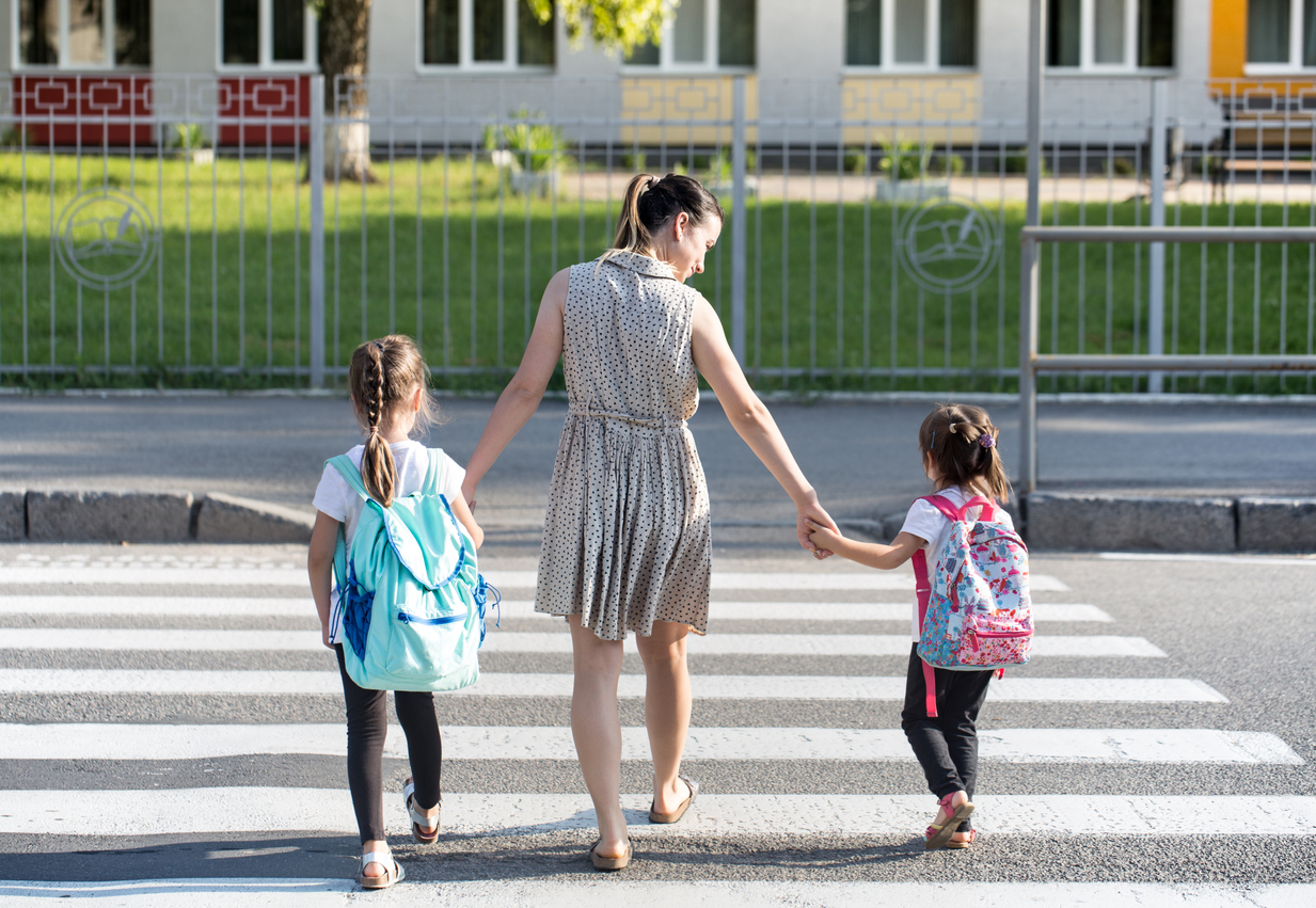 Back to school education concept with girl kids, elementary students, carrying backpacks going to class